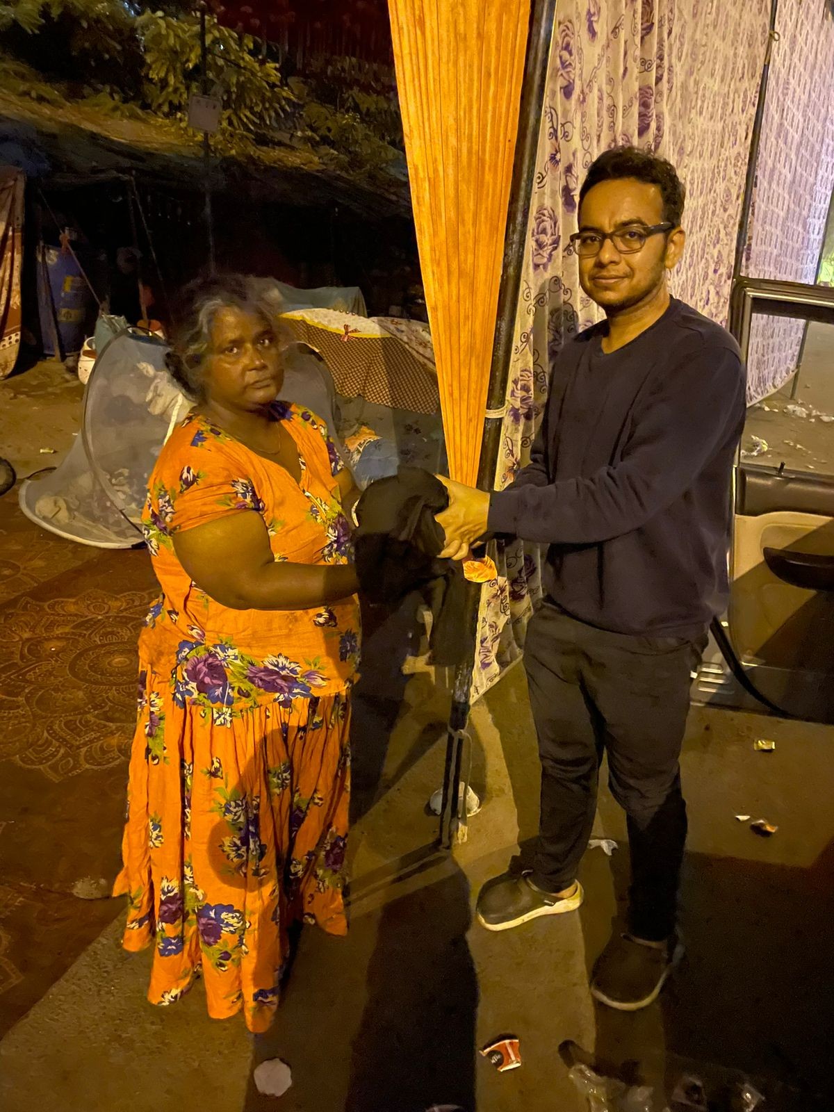 A volunteer handing clothes to a woman at night