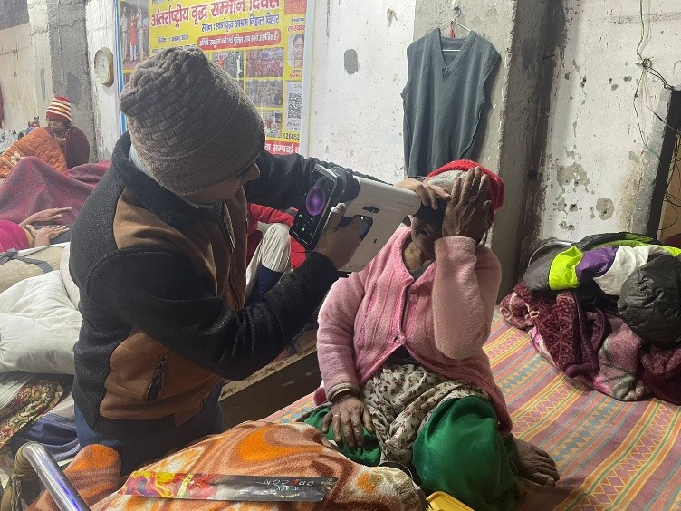 A health worker screening an elderly woman's eyes at a community health camp