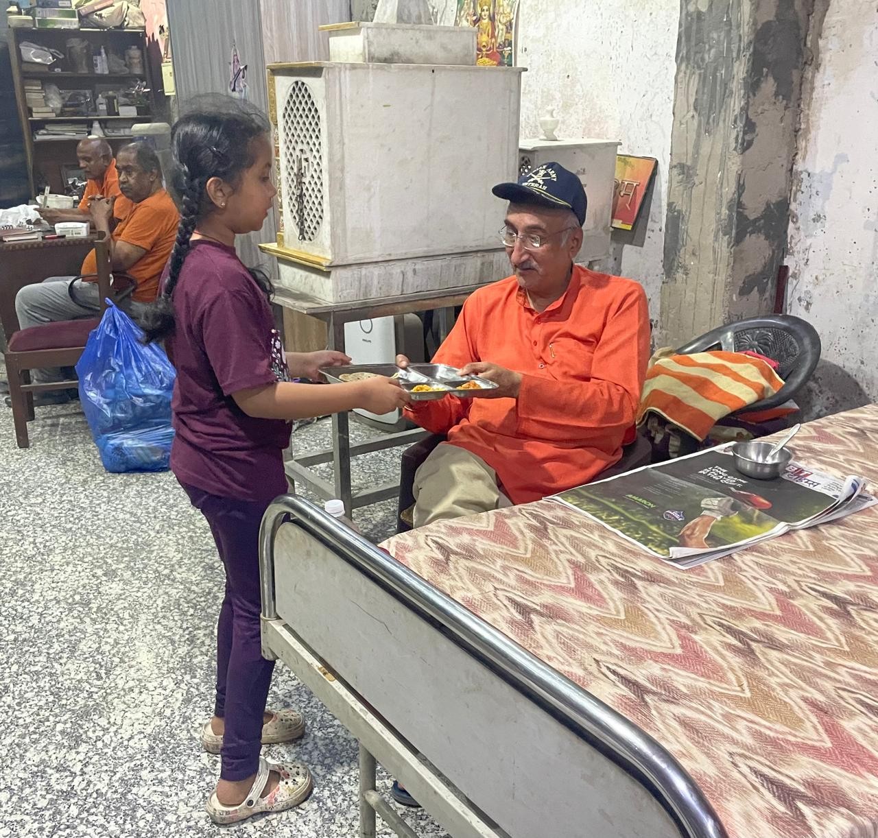 A child serving a meal to an elderly man at a care home